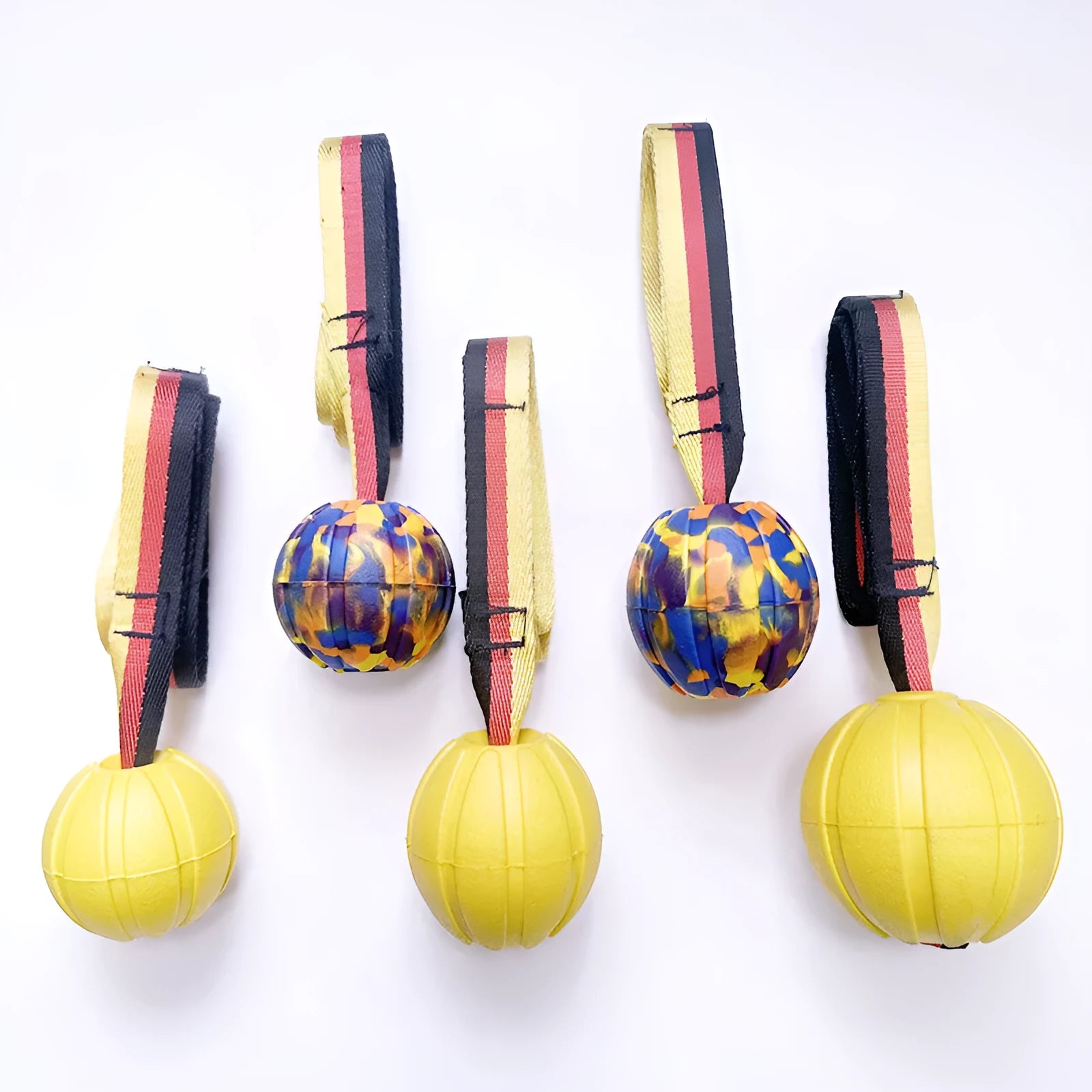 Yellow and camouflage coloured EVA floating dog ball with string in three different sizes on blue background