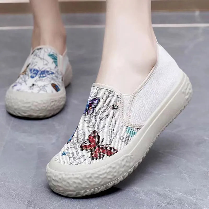Women's black and white canvas slip-on shoes with round toe and decorative stitching.