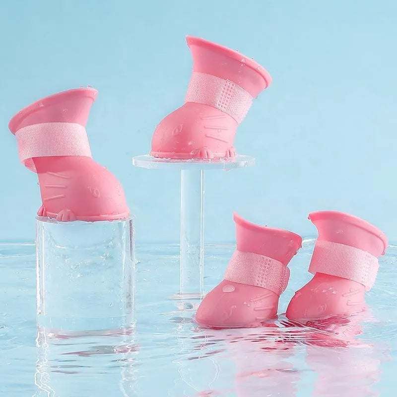 Four waterproof silicone dog rain boots in blue, grey, light blue and pink on a white background