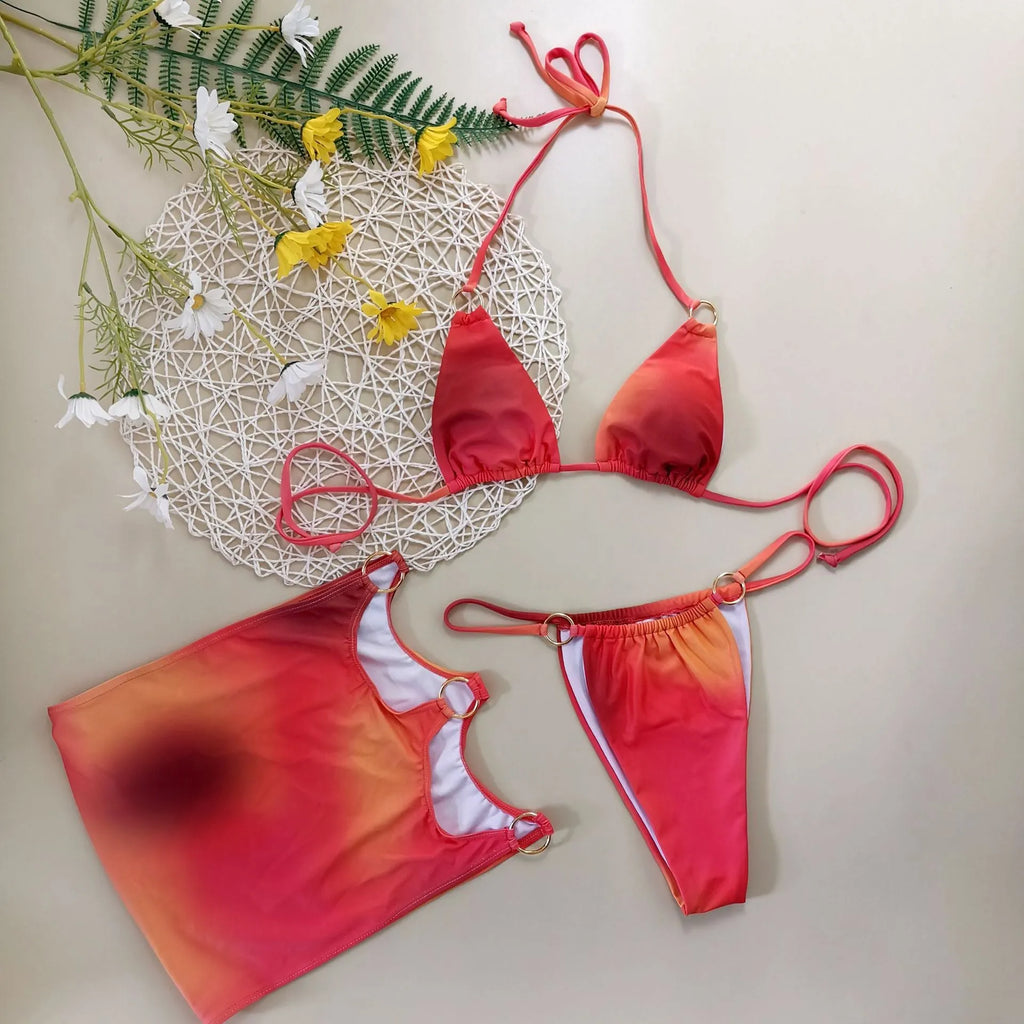 Women's tie-dye halter neck bikini set with matching detachable skirt on a beach towel