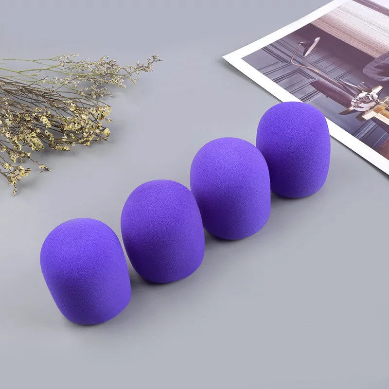 Four multicolored foam microphone windshields for handheld stage microphones on a grey background.