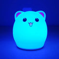 Cartoon silicone clapping night lamp in pink with USB charging cable on a bedside table