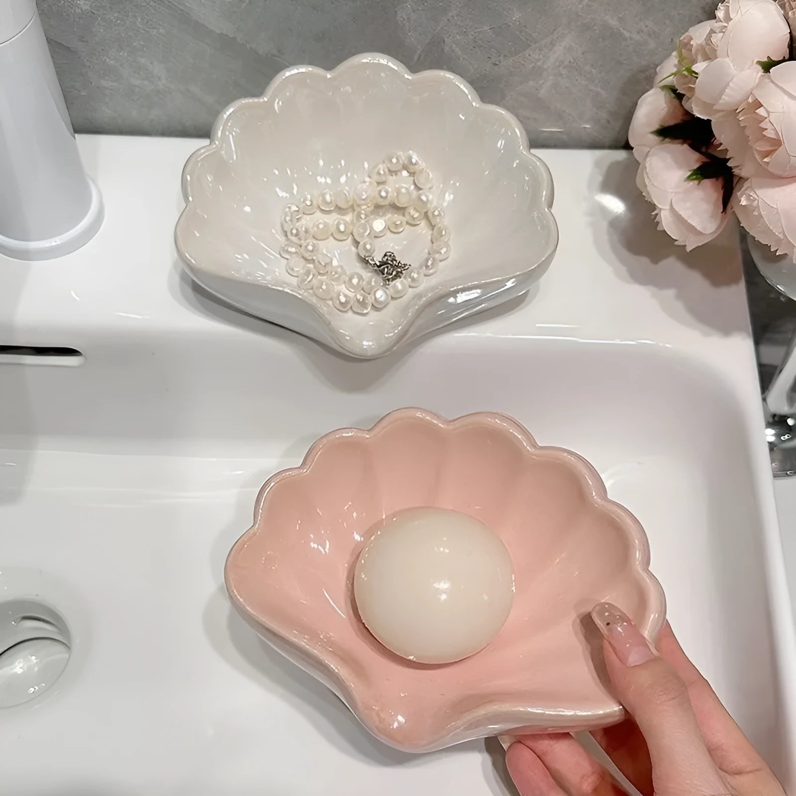 White plastic shell-shaped soap dish for bathroom vanity storage.