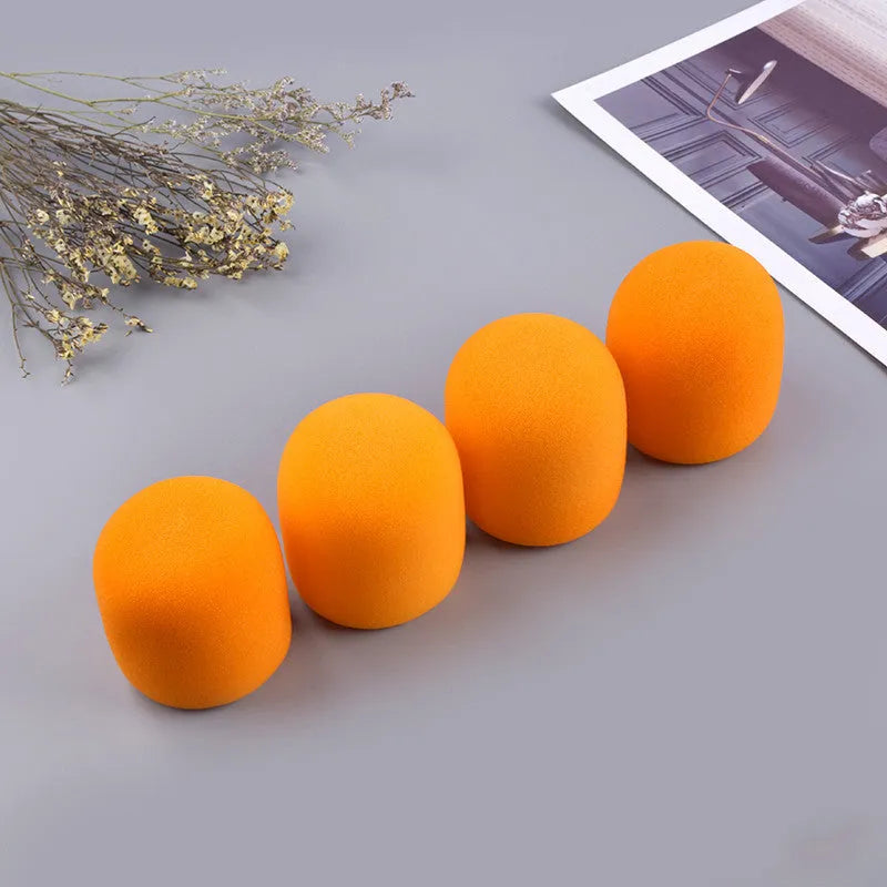 Four multicolored foam microphone windshields for handheld stage microphones on a grey background.