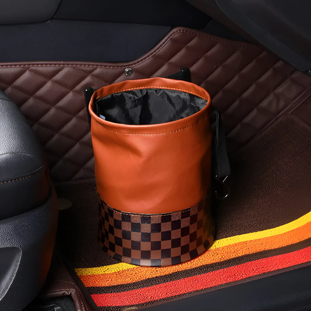 Brown leather retractable car trash can shown in a folded state with a carry handle.