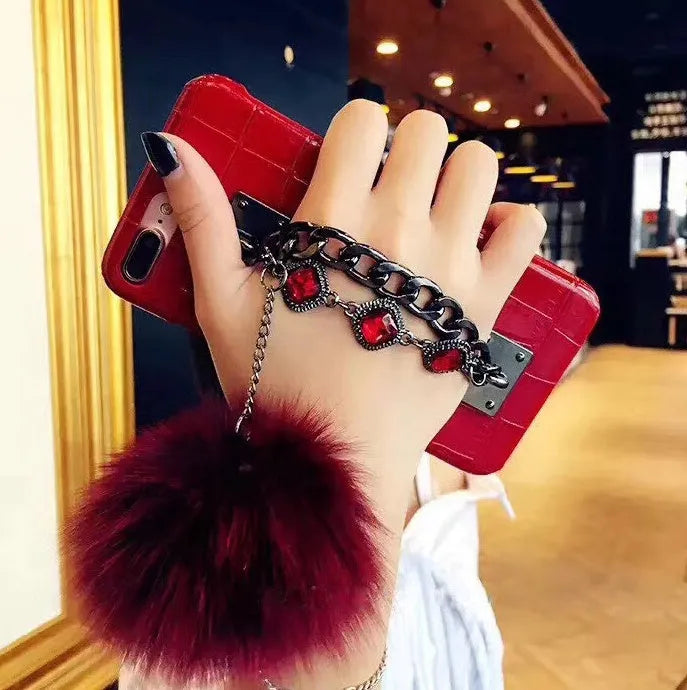Red iPhone case with fox fur ball decoration and rhinestone studded design