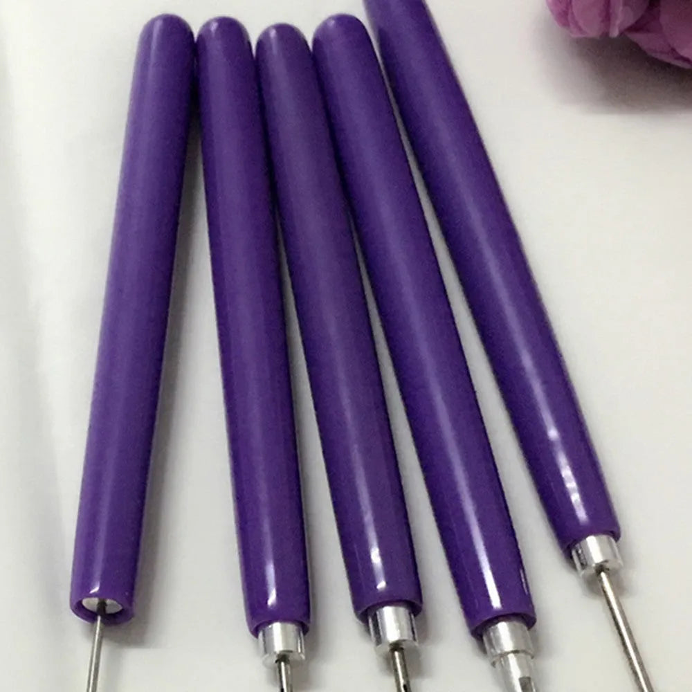 Five purple quilling pens with slotted tips and a stylus laid out on a surface