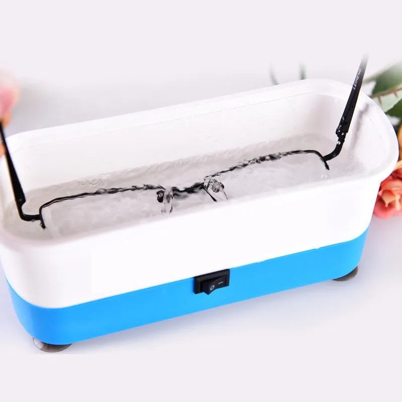 Blue plastic analog ultrasonic cleaner for glasses and contact lenses, 17x6x8 cm, with suction cups on a table