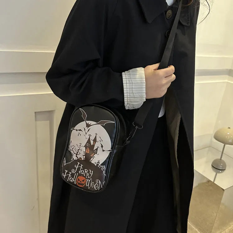 Black mini square crossbody bag with orange pumpkin, white ghost, and black bat graffiti print on the front.