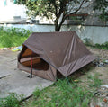 Brown A-line hiking tent pitched using trekking poles with guy ropes secured
