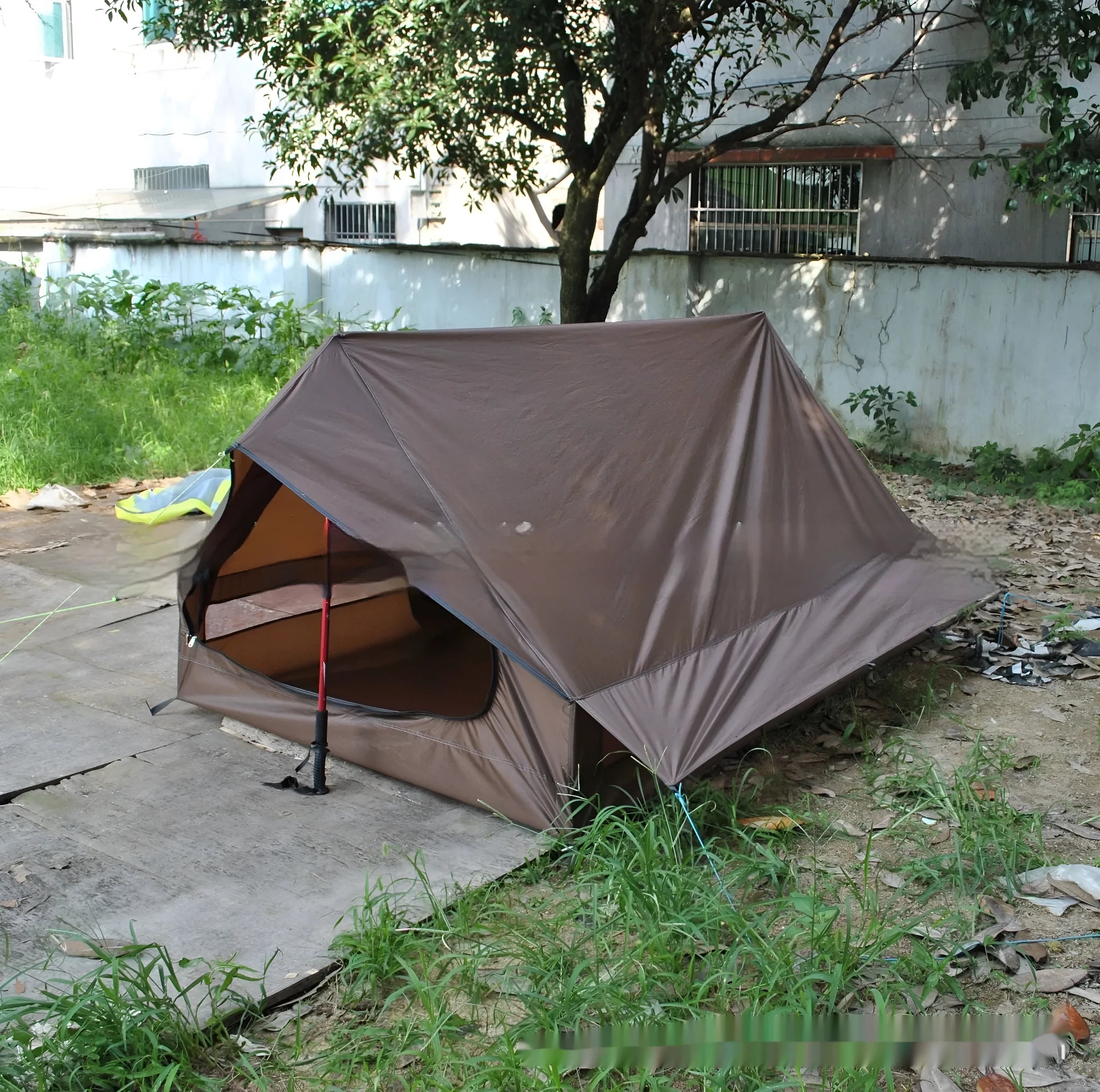 Brown A-line hiking tent pitched using trekking poles with guy ropes secured