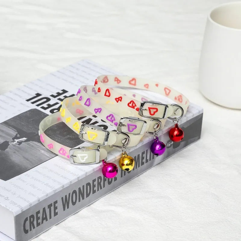 Silicone light-up cat collar with luminous fish bone and heart patterns on a pink background