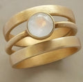 Gold-coloured geometric titanium steel ring with a micro-inlaid white chalcedony stone.
