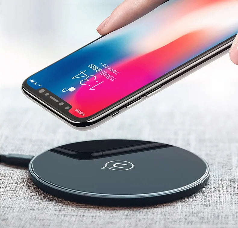 A black or white glass disc wireless charger on a table, showing its sleek design.