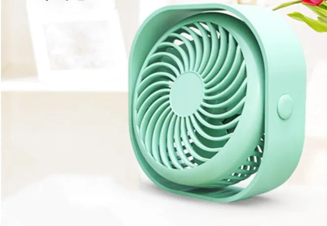 USB desk fan with 360-degree rotation in blue, on a desk next to a laptop.