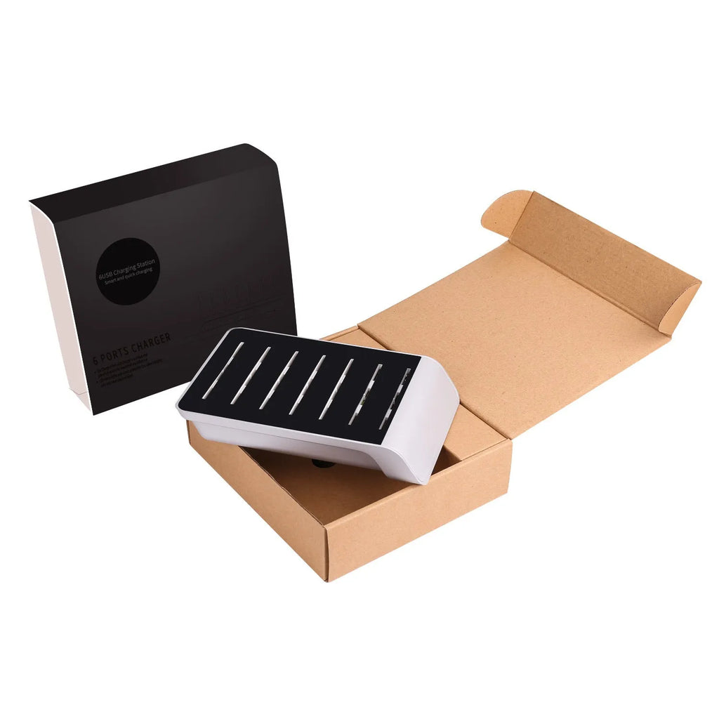 Six-port USB mobile phone charging stand in silver with multiple phones and tablets inserted, on a wooden desk