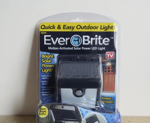 Set of four white square solar-powered LED security lights with motion sensor mounted on a brick wall