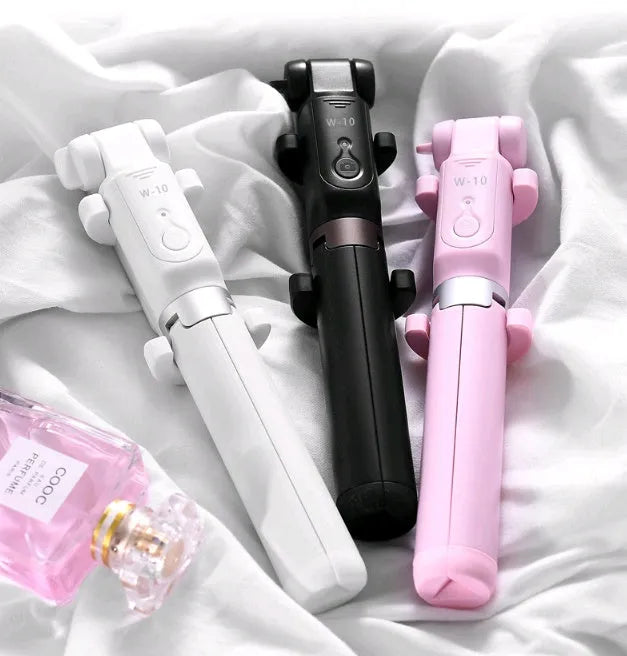 Black Bluetooth selfie stick with tripod base and remote control extended next to smartphone