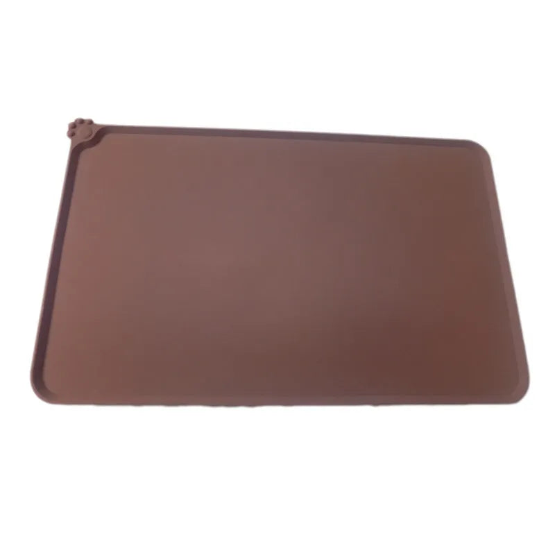 Grey silicone pet food mat with raised edges on a tile floor