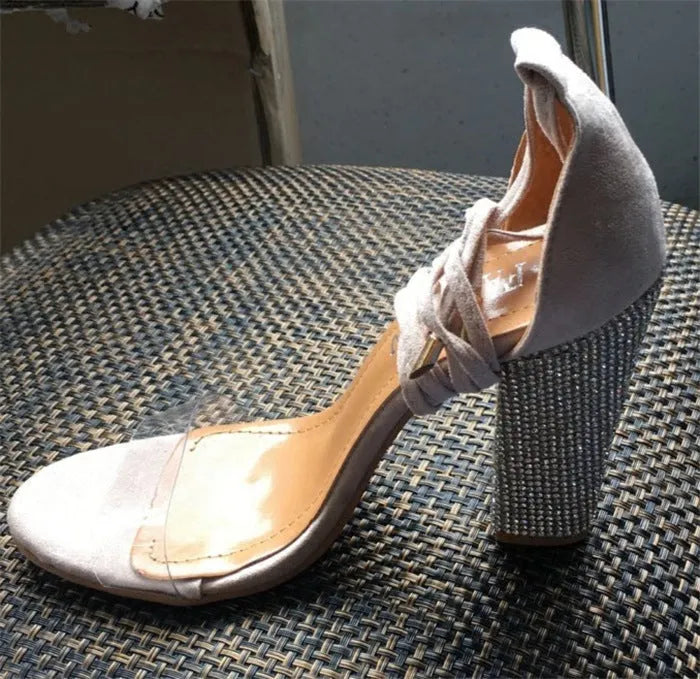 Women's black and gold pointed toe plastic stiletto high heels on a white background.