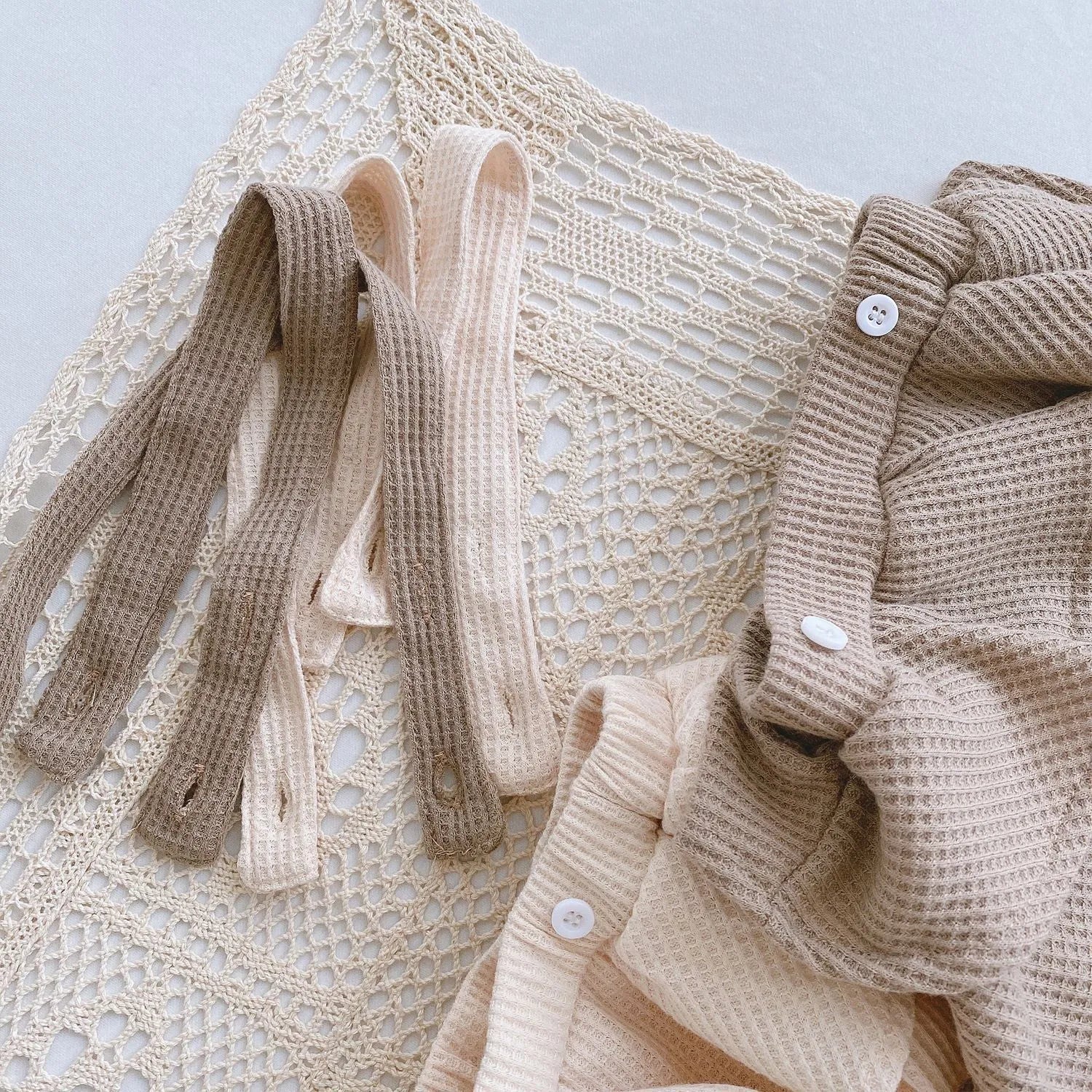 Baby romper with triangle climb style in cotton fabric showing apricot, coffee, floral and check colour options