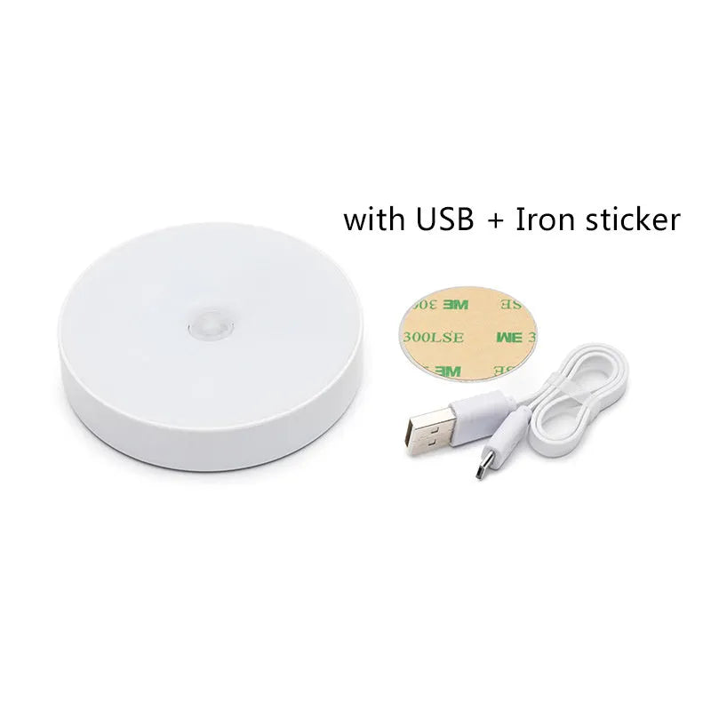 Small round beige and white LED motion sensor night light with USB charging cable and adhesive tape.