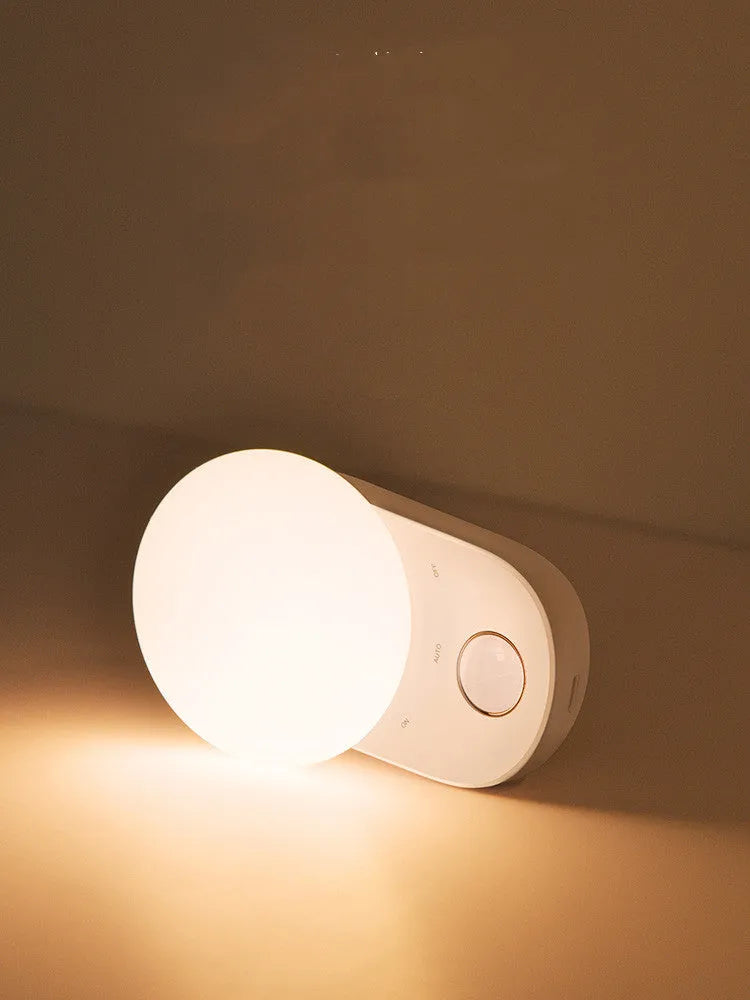 White Baseus rechargeable motion sensor bedside night light on a wooden surface.