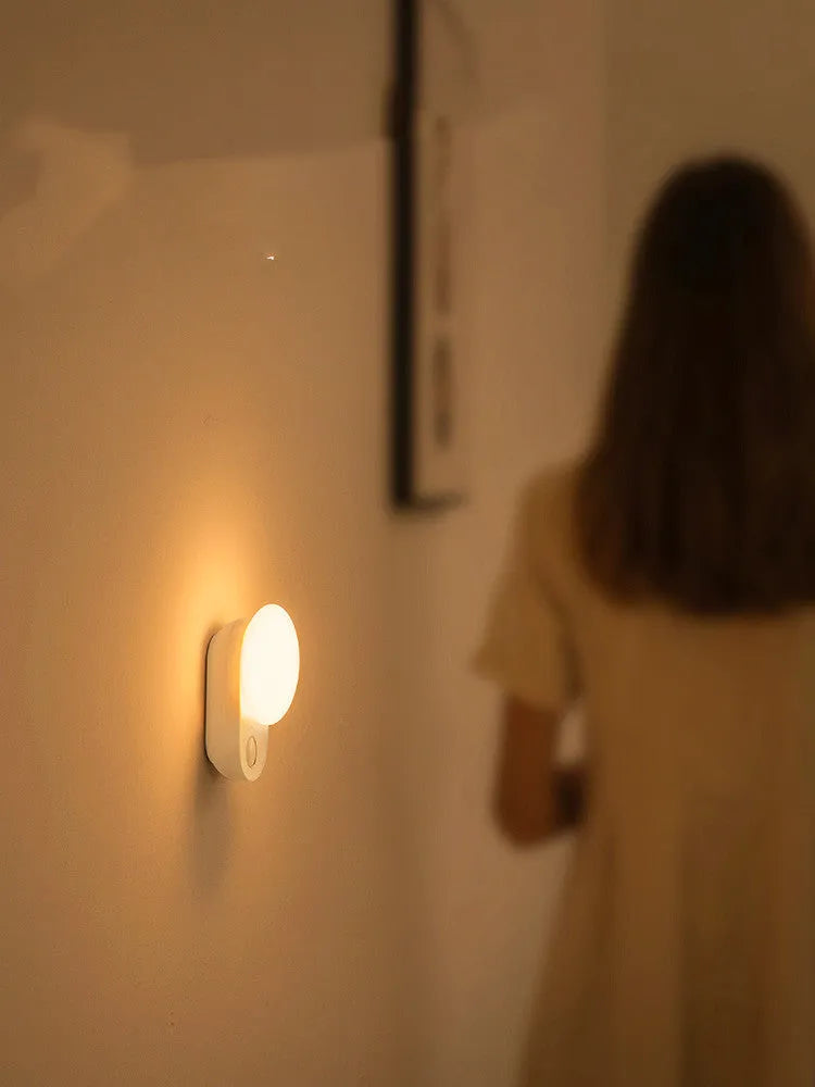 White Baseus rechargeable motion sensor bedside night light on a wooden surface.