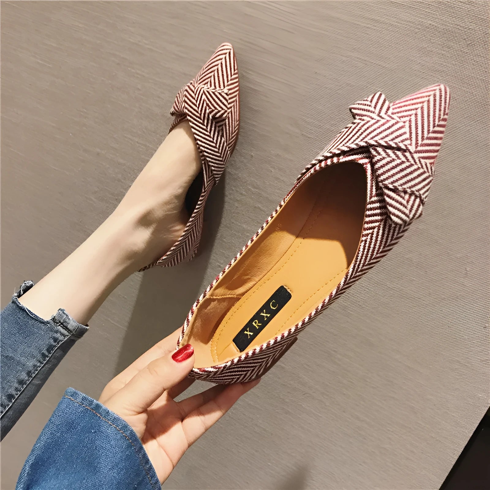 Red and black women's pointed toe shallow-mouth flats with a low flat heel on a white background.