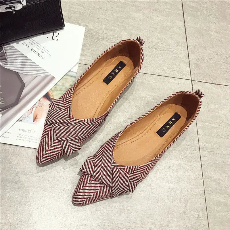Red and black women's pointed toe shallow-mouth flats with a low flat heel on a white background.
