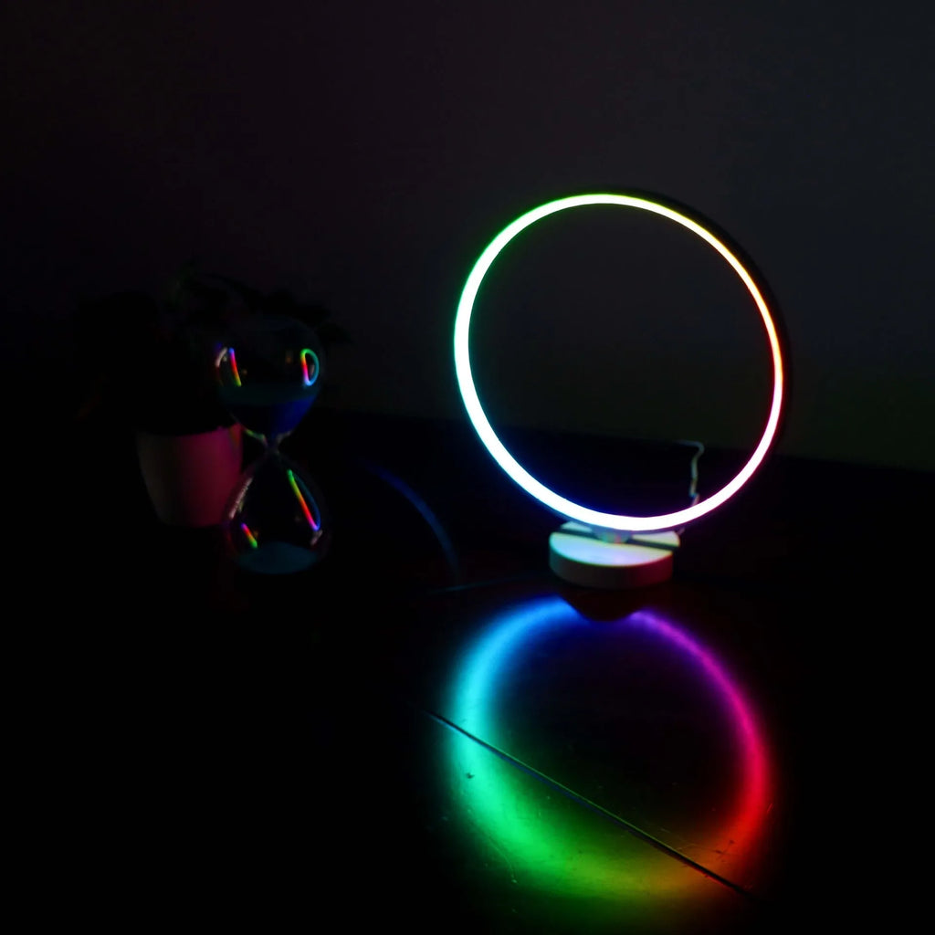 White Full Moon table lamp with remote control on a wooden surface, showing its round silicone diffuser and aluminium base.