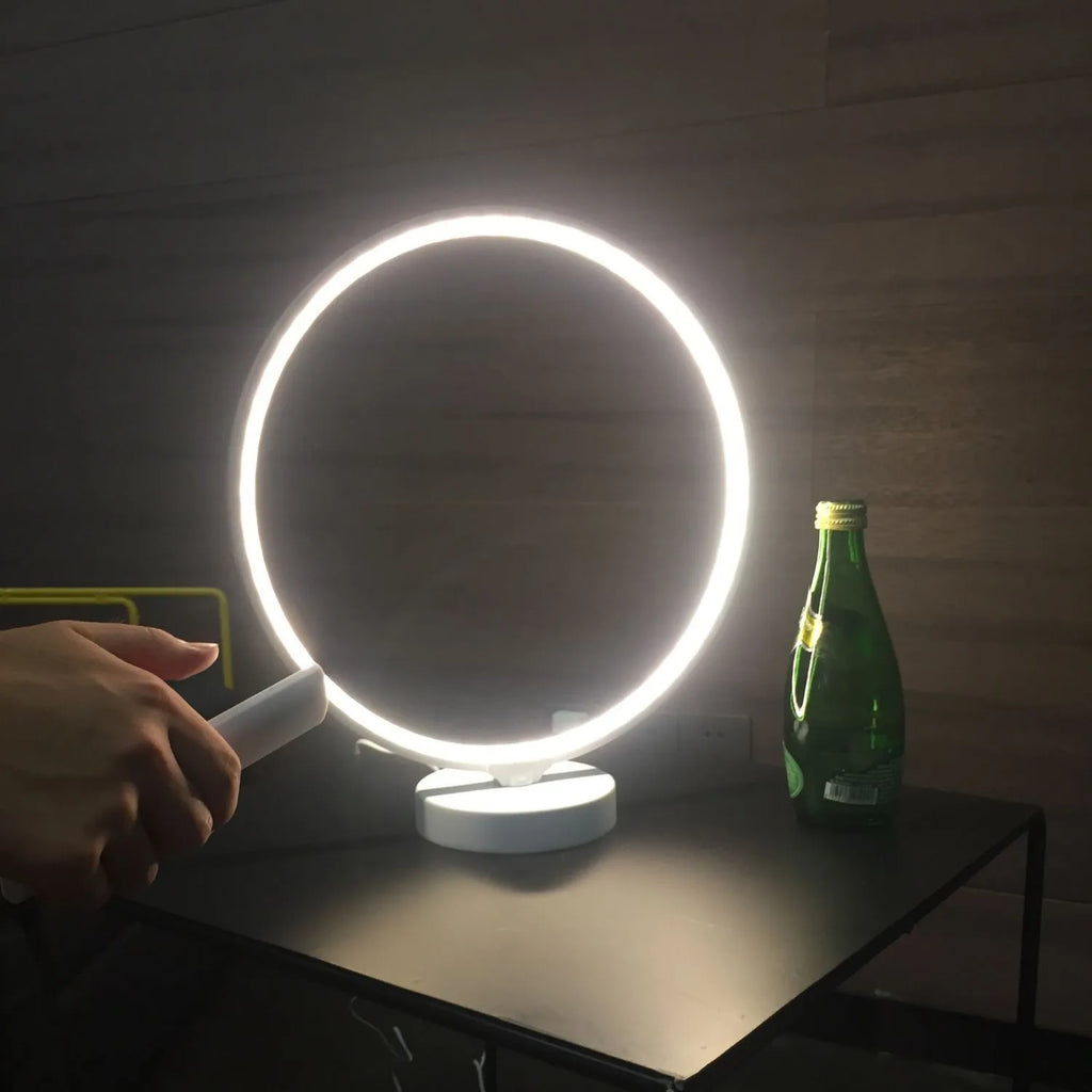 White Full Moon table lamp with remote control on a wooden surface, showing its round silicone diffuser and aluminium base.