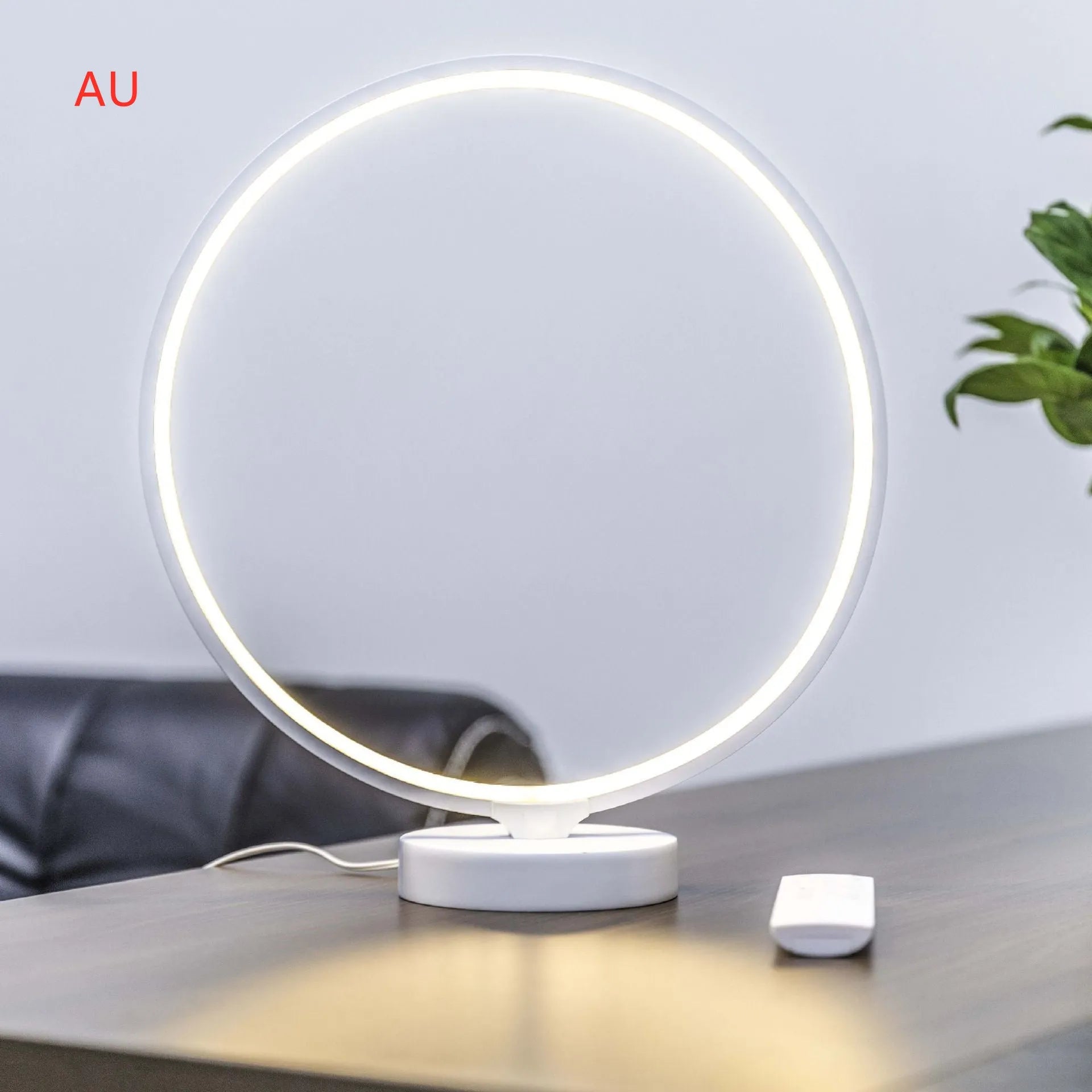 White Full Moon table lamp with remote control on a wooden surface, showing its round silicone diffuser and aluminium base.