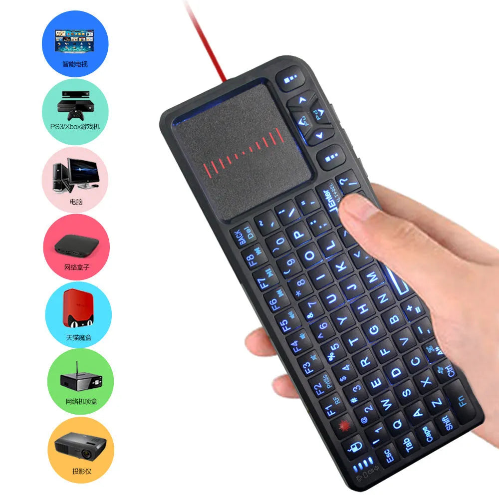 Black wireless mini keyboard with laser pointer, touch screen, and backlit keys on a desk.