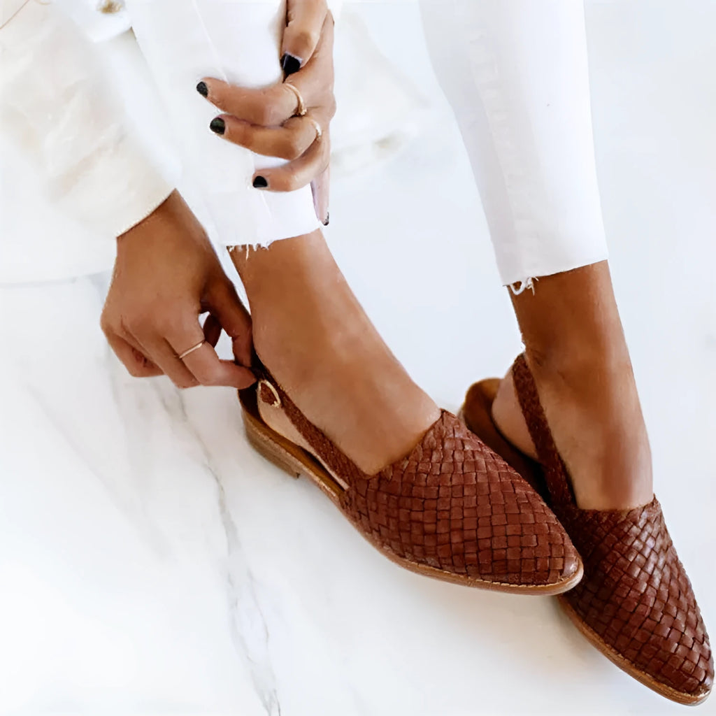 Black baotou flat sandals with a pointed toe and silver buckle closure on a rubber sole.