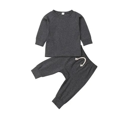 A baby wearing a blue cotton romper tracksuit set with a cartoon pattern, showing the one-piece design.