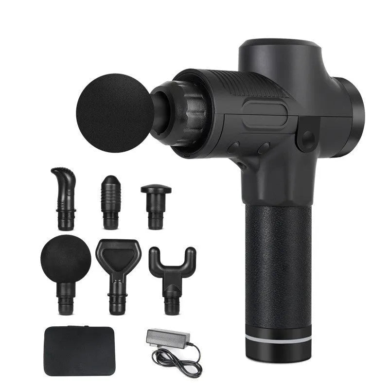 Black electric muscle massage gun with multiple interchangeable heads on a table.