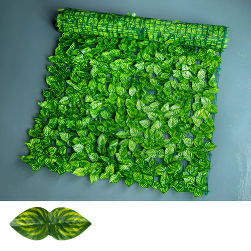 Artificial green plastic fence panel with printed leaves, used as a balcony privacy screen.