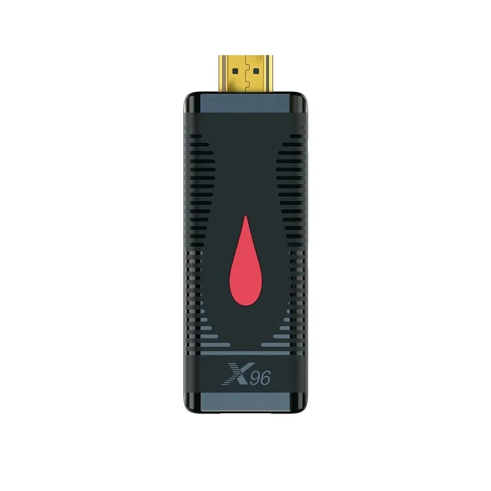 Compact black smart TV set-top box dongle with remote control, HDMI cable, and power adapter on a wooden table.