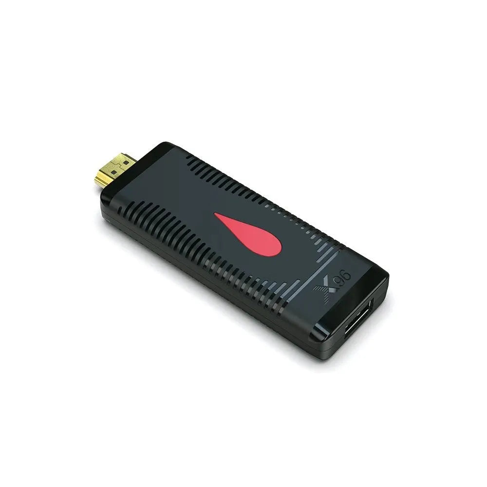 Compact black smart TV set-top box dongle with remote control, HDMI cable, and power adapter on a wooden table.