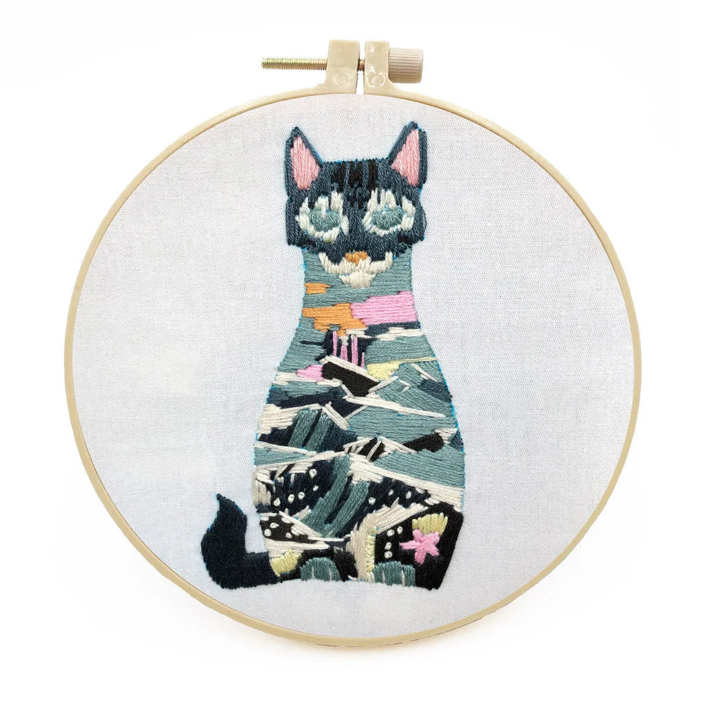 DIY embroidery kit components showing cotton fabric, coloured threads, and hoop for cat designs