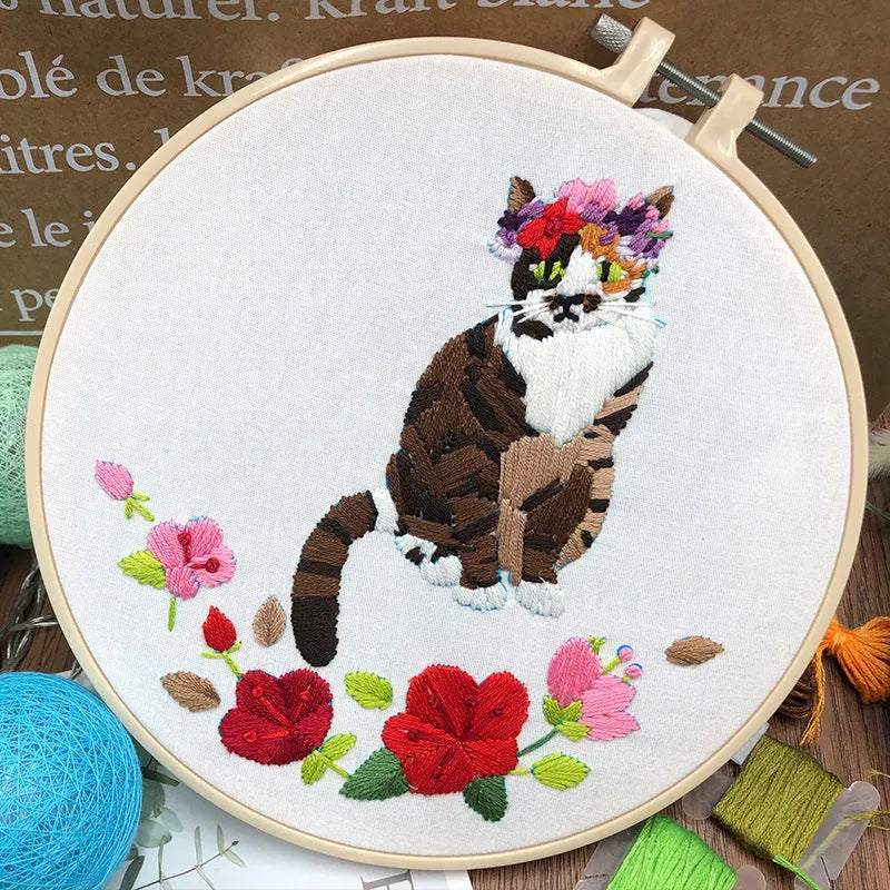 DIY embroidery kit components showing cotton fabric, coloured threads, and hoop for cat designs