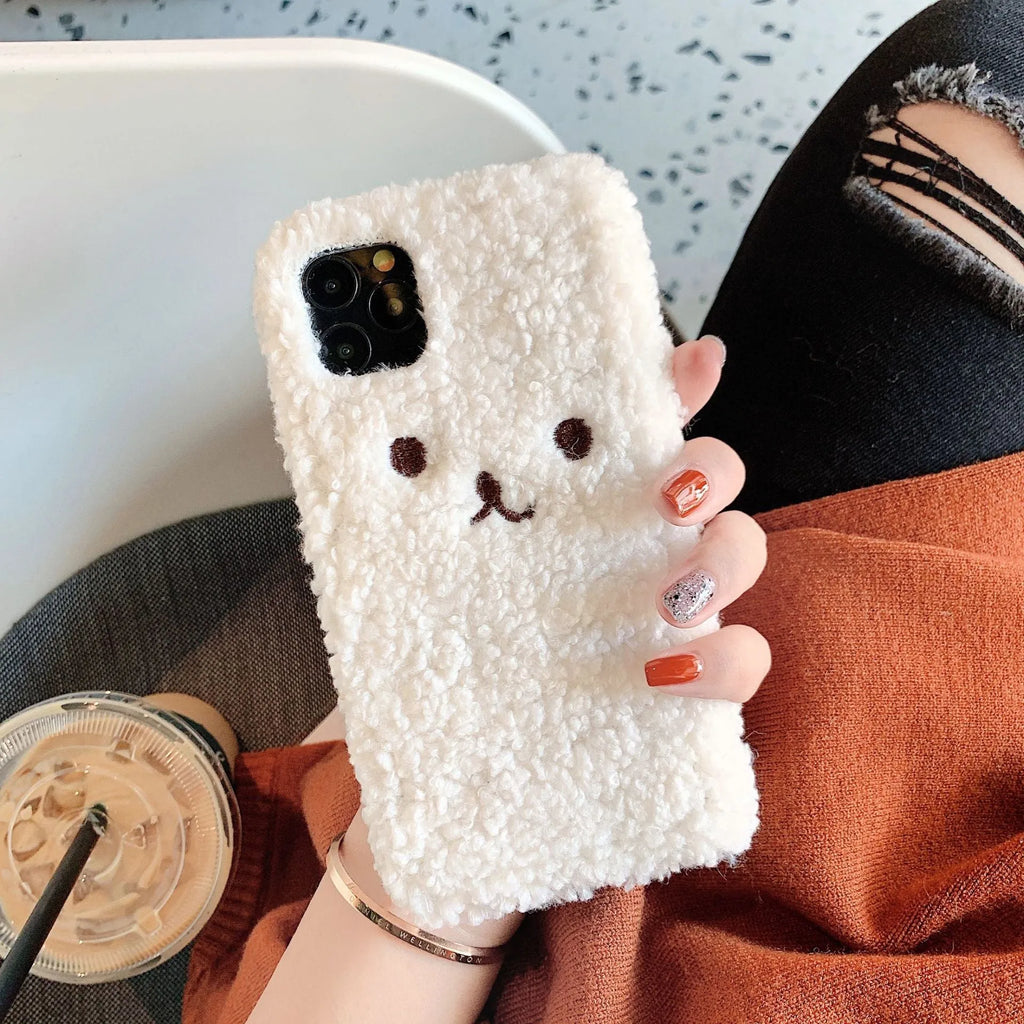 Brown embroidered plush bear face on a clear TPU phone case for iPhone, showing precise button and camera cutouts.