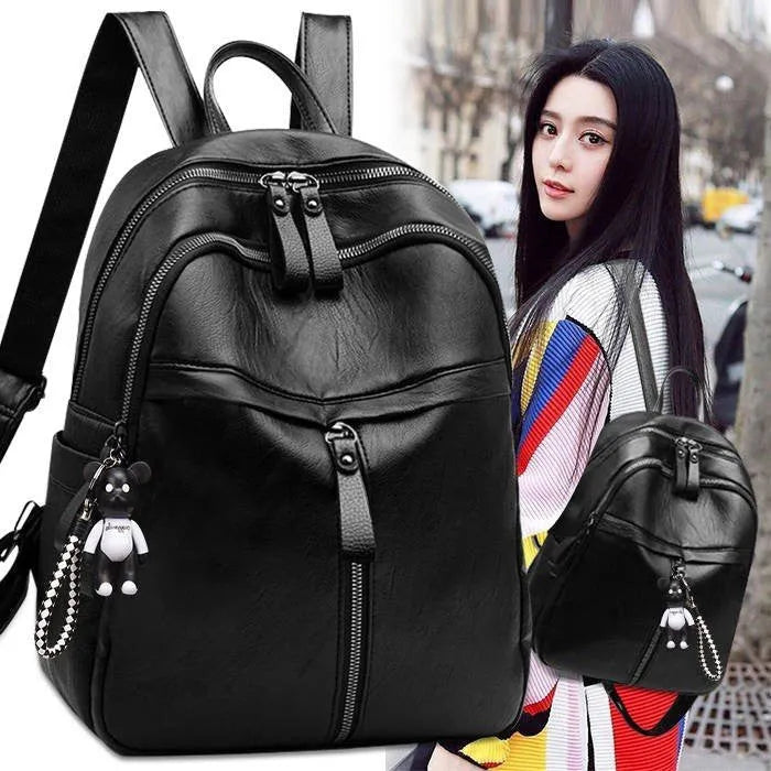 Black soft surface PU leather backpack with double straps, shown with a luggage strap accessory.