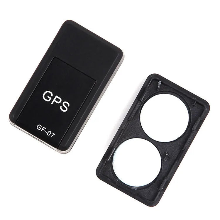 Small black magnetic GPS tracker device next to a USB charging cable on a table.