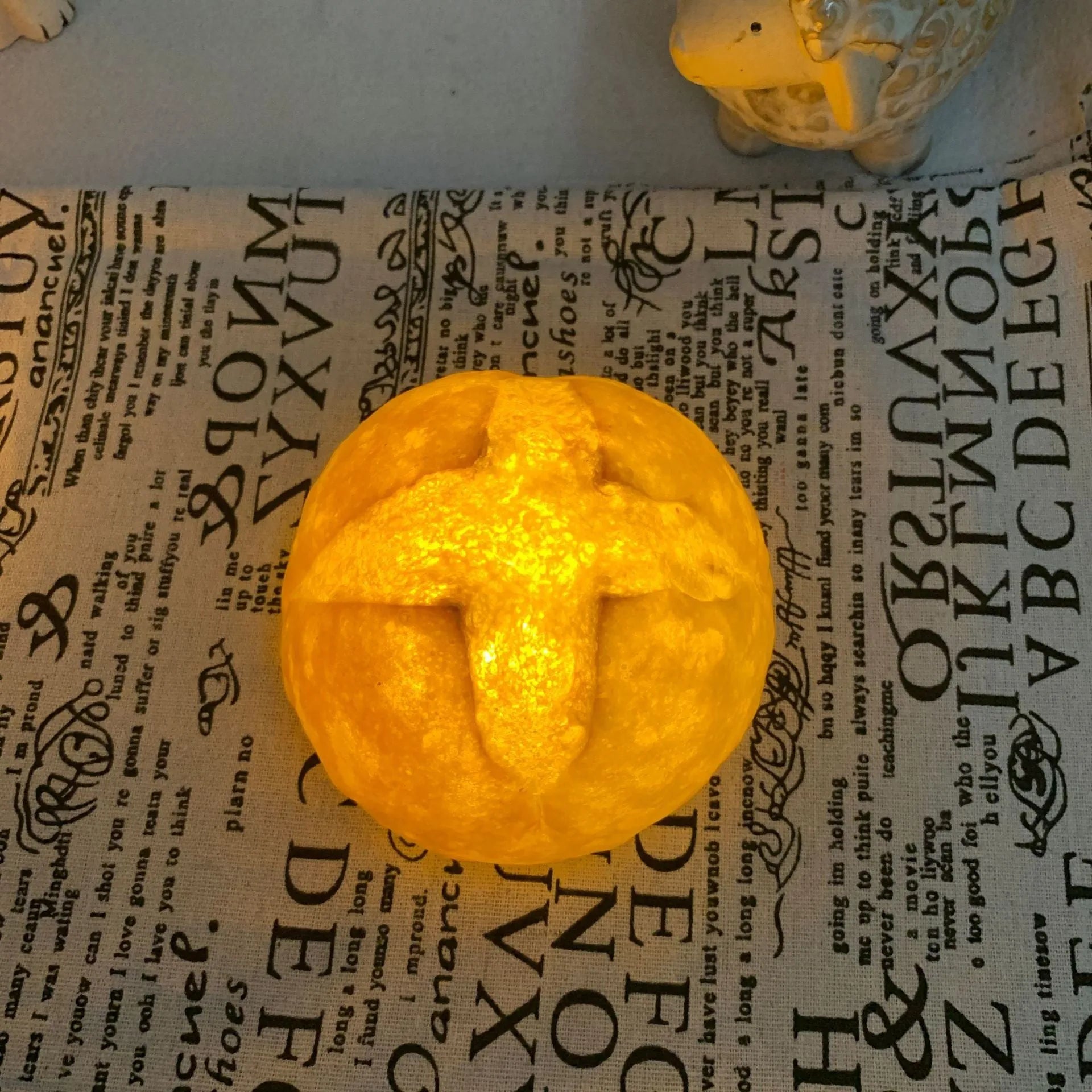 Battery-powered croissant-shaped LED night light with plastic shade on a table.