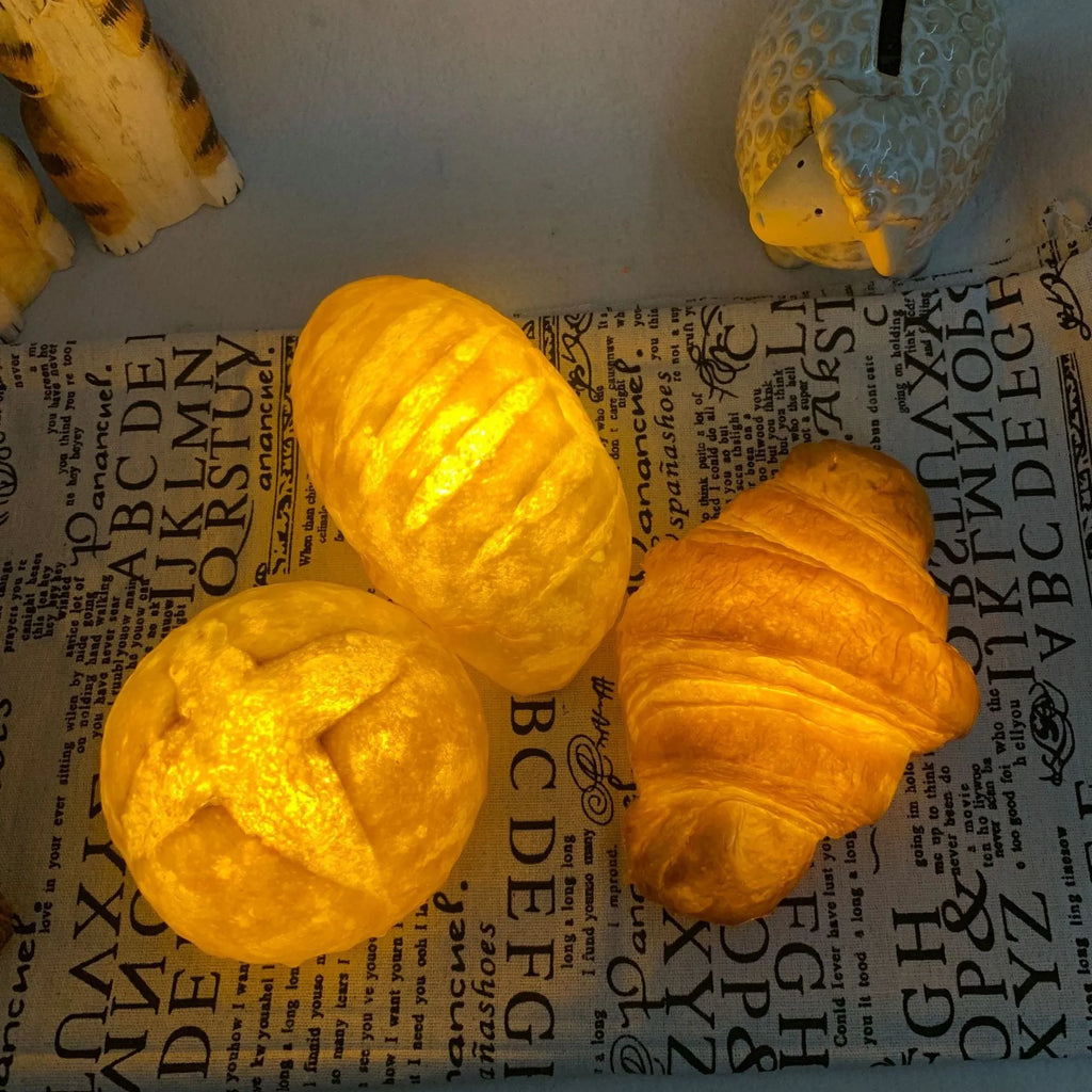 Battery-powered croissant-shaped LED night light with plastic shade on a table.