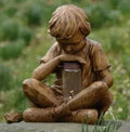 Brown natural resin tabletop statue of young boy in garden setting for indoor decoration