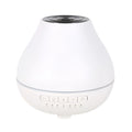 Round white Bluetooth humidifier and essential oil aroma diffuser with night light on a wooden surface.