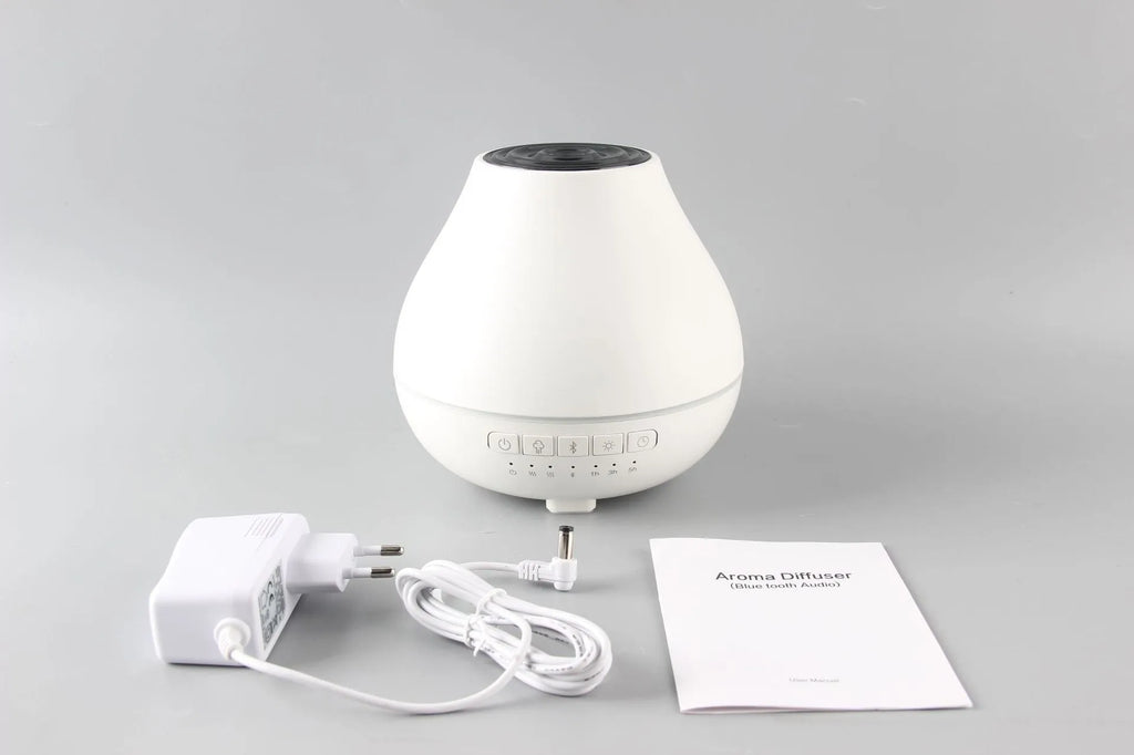 Round white Bluetooth humidifier and essential oil aroma diffuser with night light on a wooden surface.
